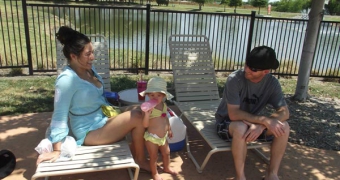 A couple and their daughter relaxing poolside at Woodcreek