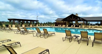 Pool deck with lounge chairs all looking to the pool and the pavilion